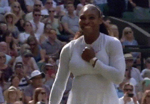 A Woman In A White Dress Is Standing In Front Of A Crowd Of People GIF