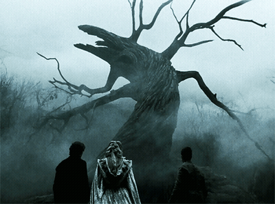 A Woman In A White Dress Is Standing In Front Of A Tree GIF
