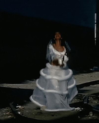 A Woman In A White Dress Is Standing In The Water With Her Arms In The Air GIF