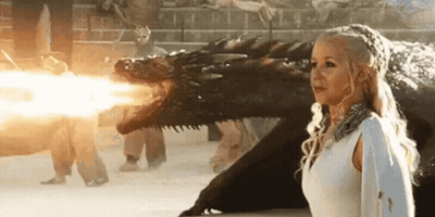 A Woman In A White Dress Is Standing Next To A Dragon That Is Shooting Fire . GIF