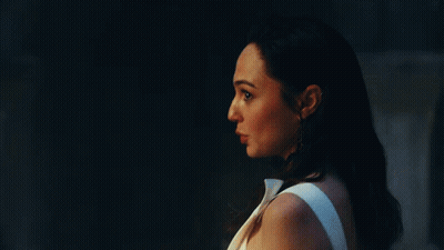 A Woman In A White Dress Is Standing Next To A Man In A Dark Room . GIF