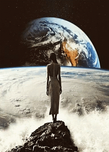 A Woman In A White Dress Is Standing On A Rock In Front Of The Earth GIF