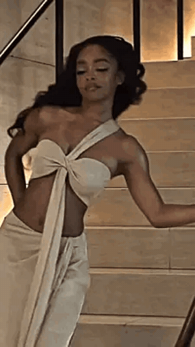 A Woman In A White Dress Is Standing On Stairs . GIF