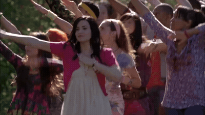 A Woman In A White Dress Is Surrounded By Other Women GIF
