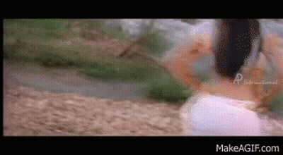 A Woman In A White Dress Is Walking Down A Path . GIF