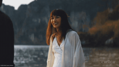 A Woman In A White Dress Is Walking In The Water With The Creator Written In The Corner GIF