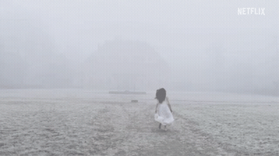 A Woman In A White Dress Is Walking On A Snowy Beach . GIF