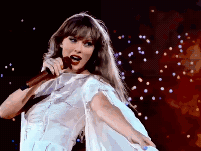 A Woman In A White Dress Singing Into A Microphone On A Stage GIF