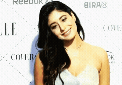 A Woman In A White Dress Smiles In Front Of Reebok And Bira GIF