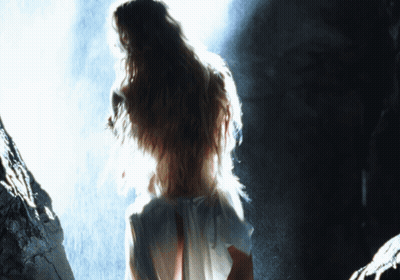 A Woman In A White Dress Stands In A Dark Room GIF