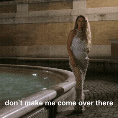 A Woman In A White Dress Stands In Front Of A Fountain With The Words " Don T Make Me Come Over There " GIF