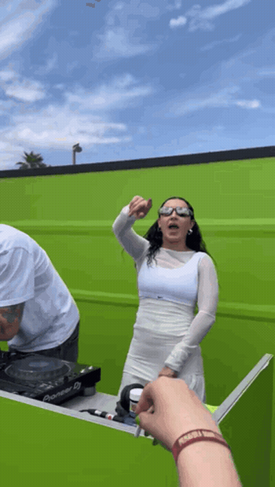 A Woman In A White Dress Stands In Front Of A Green Wall GIF