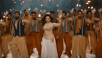 A Woman In A White Dress Stands In Front Of A Group Of Men GIF
