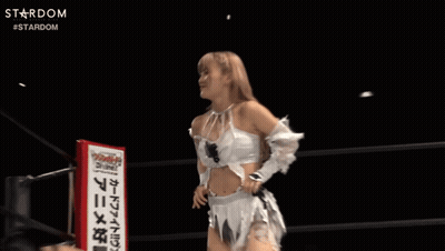 A Woman In A White Dress Stands In Front Of A Sign That Says Divine GIF