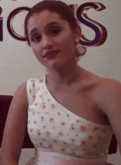 A Woman In A White Dress Stands In Front Of A Sign That Says ' Icons ' GIF