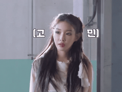 A Woman In A White Dress Stands In Front Of A Wall With Chinese Writing On It GIF