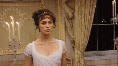 A Woman In A White Dress Stands In Front Of Candles GIF