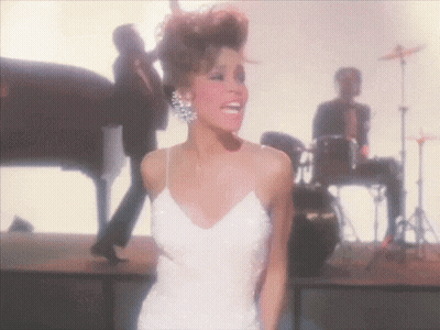 A Woman In A White Dress Stands On A Stage GIF