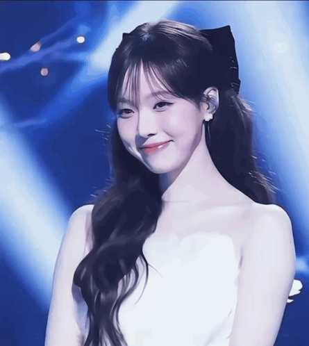 A Woman In A White Dress With A Black Bow In Her Hair Smiles GIF