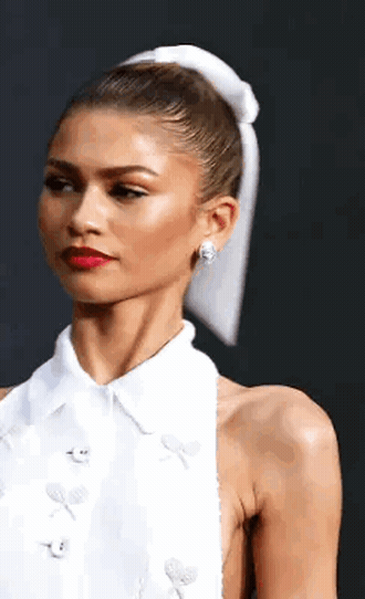 A Woman In A White Dress With A White Bow In Her Hair . GIF