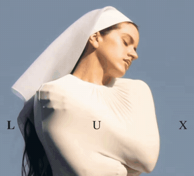 A Woman In A White Dress With The Letters L U And X On Her Chest GIF