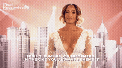 A Woman In A White Dress With The Words " Spring Summer Or September I 'M The One You Always Remember " Behind Her GIF