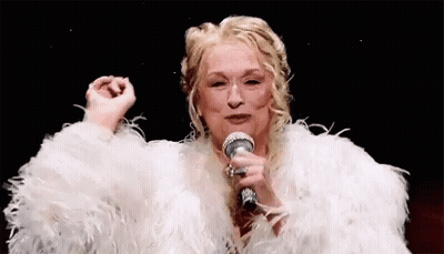 A Woman In A White Fur Coat Is Holding A Microphone . GIF