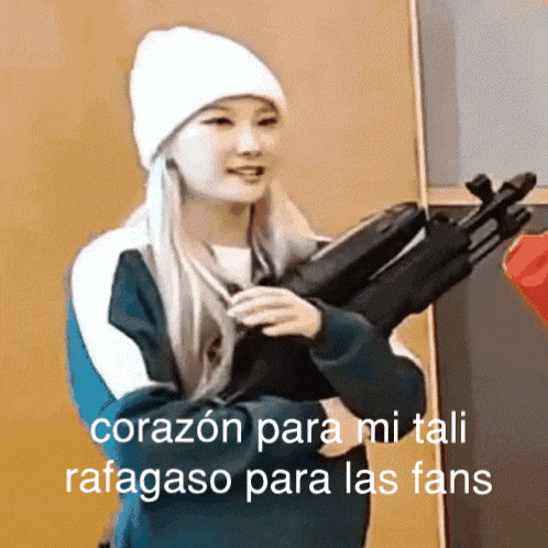 A Woman In A White Hat Is Holding A Gun And The Caption Says " Corazon Para Mi Tali Rafagoso Para Las Fans " GIF