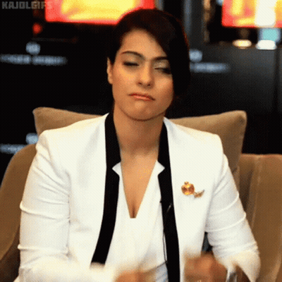 A Woman In A White Jacket And Black Tie Is Sitting On A Chair GIF