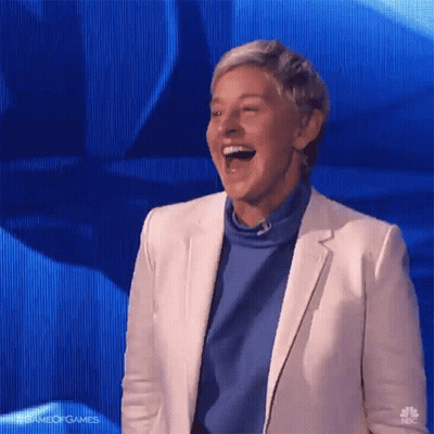 A Woman In A White Jacket And Blue Sweater Is Laughing GIF