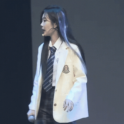 A Woman In A White Jacket And Tie Stands Next To A Man In A Black Suit GIF