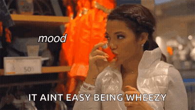 A Woman In A White Jacket Is Holding A Red Object In Her Mouth And Says " It Aint Easy Being Wheezy " GIF
