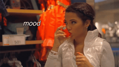 A Woman In A White Jacket Is Holding A Red Object In Her Mouth And The Word Mood Is Above Her GIF