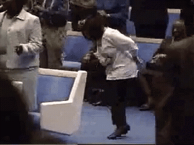 A Woman In A White Jacket Is Kneeling Down In A Crowd Of People GIF
