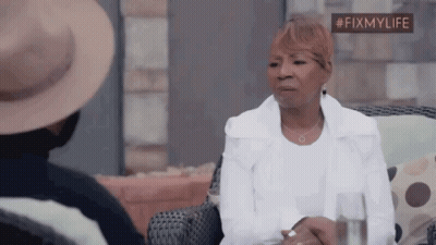 A Woman In A White Jacket Is Sitting In A Chair With A Glass Of Water . GIF