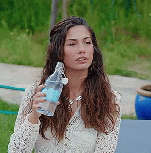 A Woman In A White Lace Top Is Holding A Clear Bottle Of Water GIF