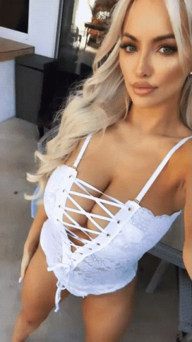 A Woman In A White Lace Up Top Is Taking A Picture Of Herself GIF