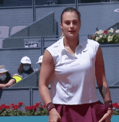 A Woman In A White Nike Shirt Is Holding A Tennis Racquet On A Tennis Court GIF