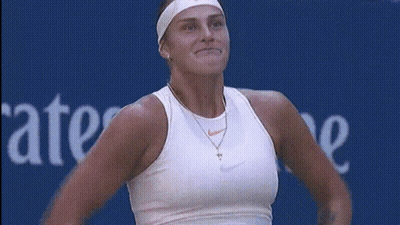 A Woman In A White Nike Tank Top Stands In Front Of A Blue Sign That Says Ate GIF