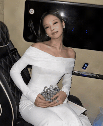 A Woman In A White Off The Shoulder Dress Is Sitting In A Car GIF