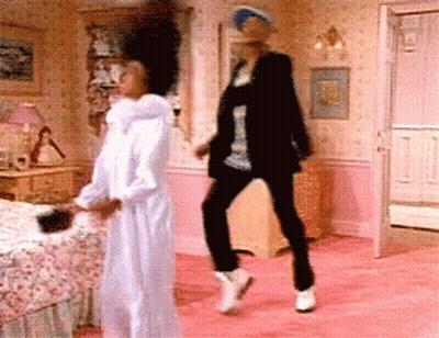 A Woman In A White Robe Is Dancing With A Man In A Black Jacket GIF