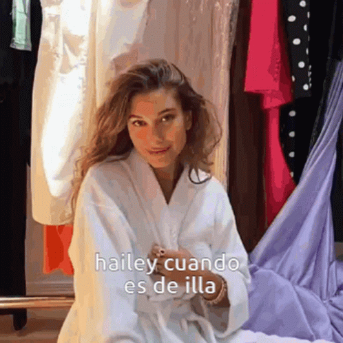 A Woman In A White Robe Is Sitting In Front Of A Closet With The Words Hailey Cuando Es De Illa Written On It GIF