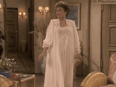 A Woman In A White Robe Is Standing In A Living Room With A Sign That Says Dr Pflaumisan GIF