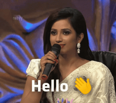 A Woman In A White Saree Is Holding A Microphone And Says " Hello " GIF