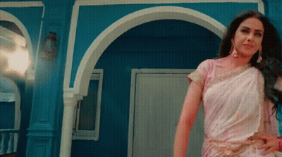 A Woman In A White Saree Stands In Front Of A Blue Wall GIF