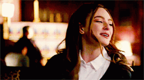 A Woman In A White Shirt And Black Jacket Is Laughing With Her Eyes Closed . GIF