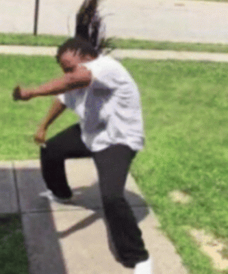 A Woman In A White Shirt And Black Pants Stands On A Sidewalk GIF