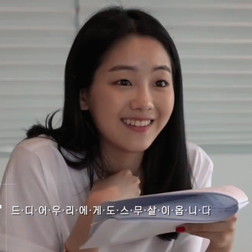 A Woman In A White Shirt Holds A Piece Of Paper In Her Hand GIF