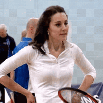 A Woman In A White Shirt Holds A Tennis Racquet In Her Hand GIF