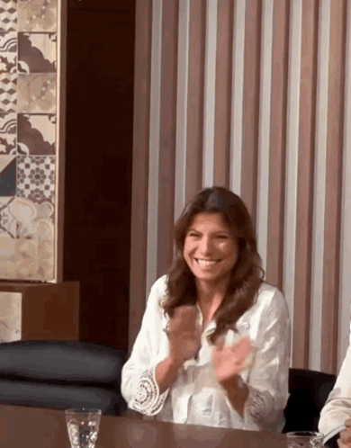 A Woman In A White Shirt Is Clapping Her Hands GIF